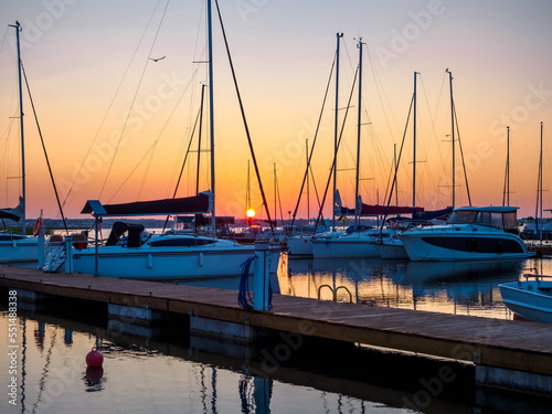 Fototapeta Naklejka Na Ścianę i Meble -  dawn landscape of quayside with jetty full of sailing yachts, calm, tranquil and serenity waterfront view