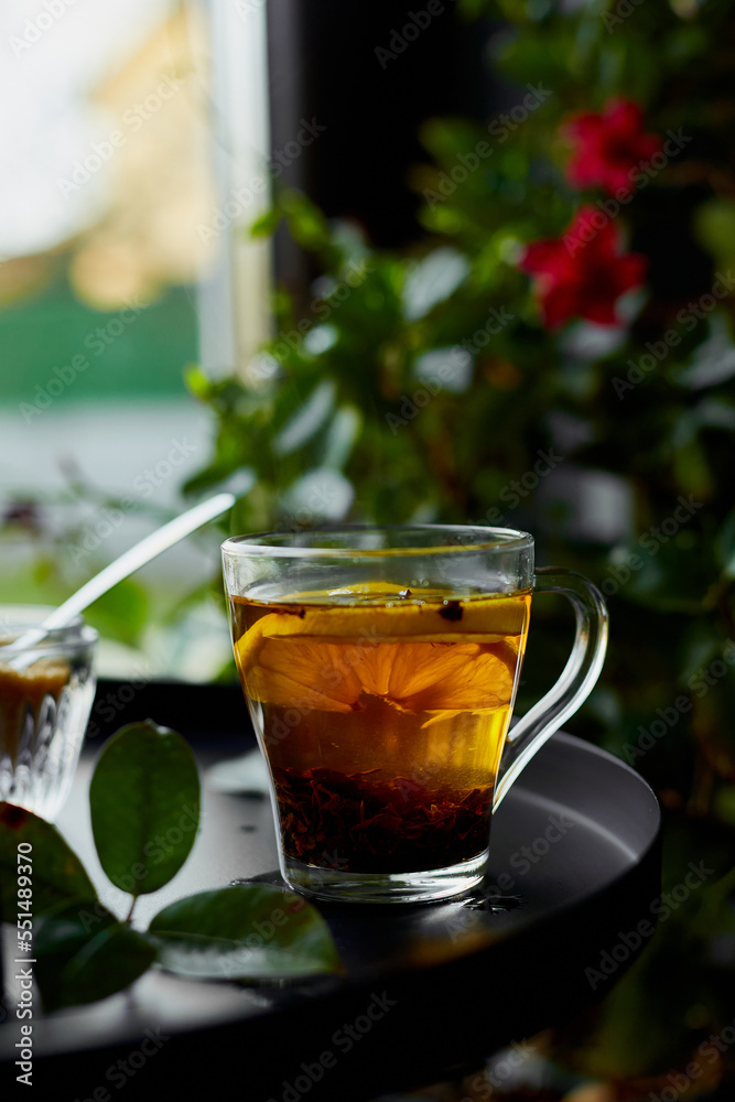 Glass cup of hot black tea lemon on dark background with steam near window, cozy warm, relaxing. Glass cup of hot black tea lemon on dark background with steam near window, cozy warm, relaxing.