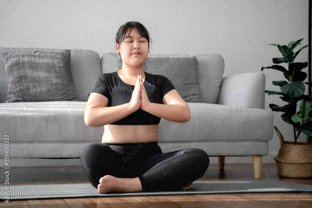 Asian chubby woman sitting on the floor in living room practice yoga lesson. female having meditate training class. Asian chubby woman sitting on the floor in living room practice yoga lesson. female having meditate training class.