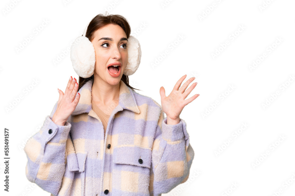 Young caucasian woman wearing winter muffs over isolated chroma key background with surprise facial expression Young caucasian woman wearing winter muffs over isolated chroma key background with surprise facial expression