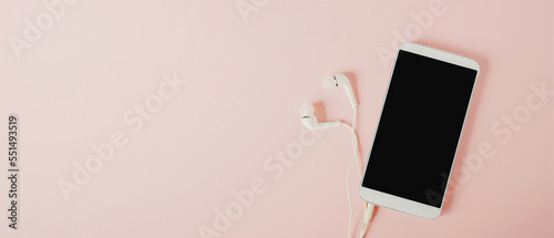 top view of white smartphone with clopping path on screen  and earphone on sweet pink background including copy space