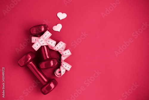 Two red dumbbells, white measuring tape, hearts on red background with copy space. Concept of Valentines day, healthy lifestyle, giving gifts, love of sports, shopping. viva magenta