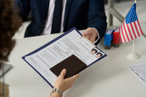 Close up of woman handing visa application form to worker in US Immigration office