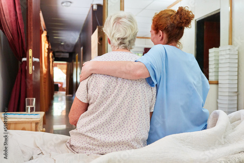 Caring nurse hugging sick old woman photo
