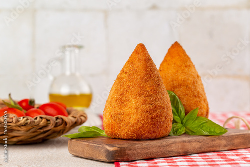 Italian rice balls stuffed, coated with breadcrumbs and deep fried.  Conical-shaped arancini.  Filled with ragu, minced meat, caciocavallo cheese and green peas. Sicilian photo
