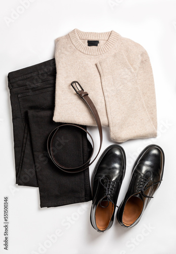 Men's wool beige sweater, black jeans, boots, leather belt. Set of comfortable casual winter or autumn clothes on a light background, flat lay.