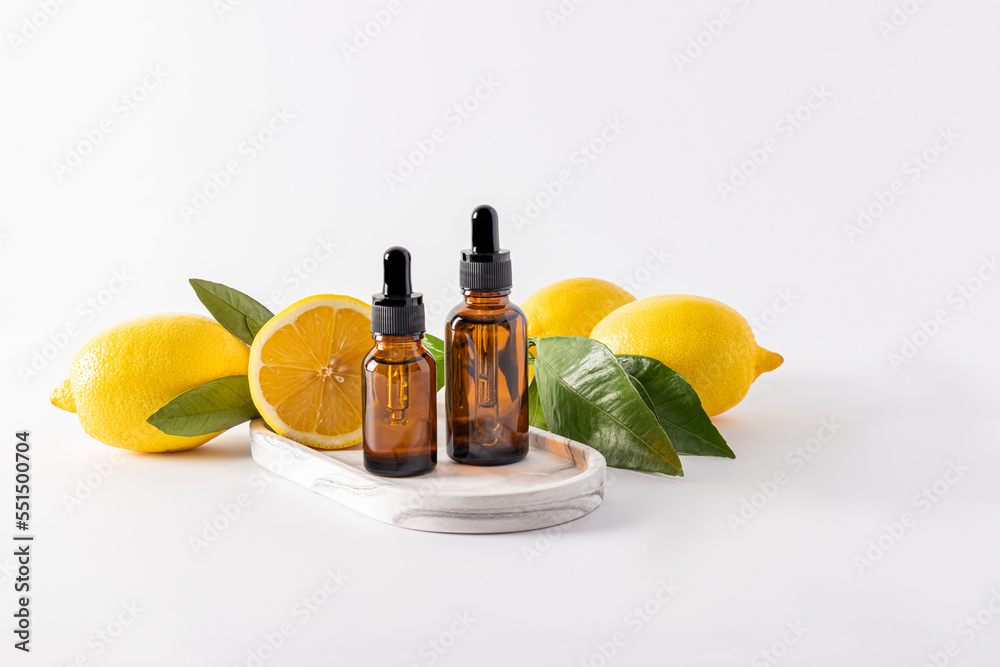 two bottles of dark glass with a dropper with cosmetic bleach stand on a plaster white tray among ripe lemons. two bottles of dark glass with a dropper with cosmetic bleach stand on a plaster white tray among ripe lemons.