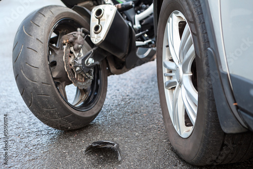 Motorcycle accident close-up view, broken parts laying on asphalt road