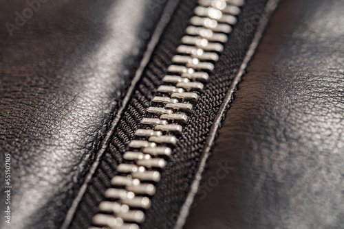 Zipper closure with metal teeth, on faux leather jacket close-up, selective focus
