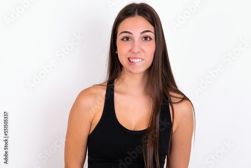 Young caucasian woman wearing sportswear over white background being nervous and scared biting lips looking camera with impatient expression, pensive.