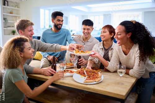 Friends Having Fun At Home In Kitchen Eating Homemade Pizzas