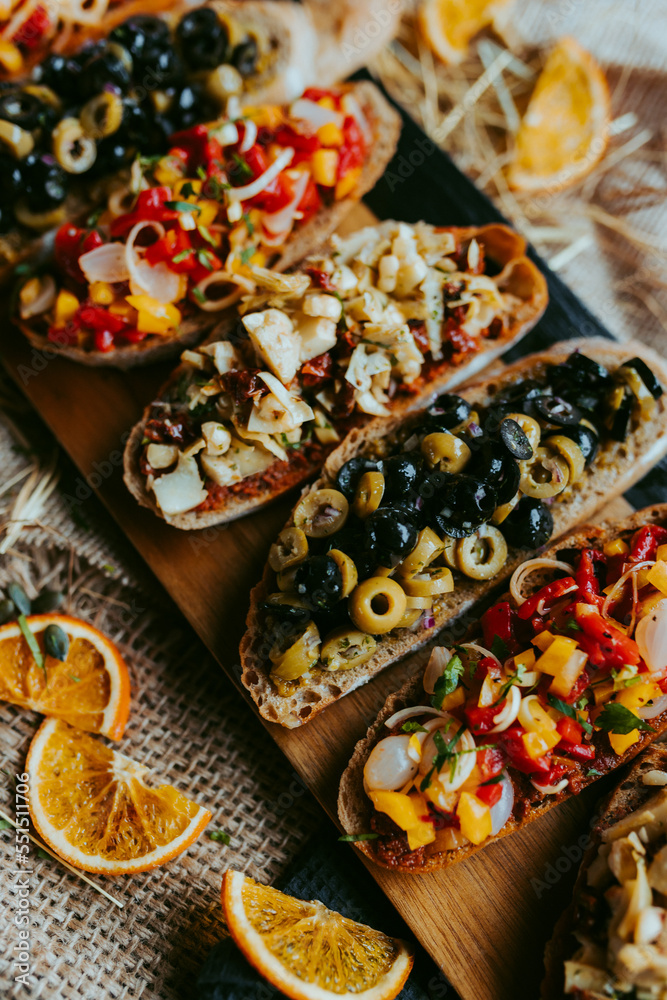Brushetta set for party, Variety of small sandwiches with ,mushrooms, tomatoes, parmesan cheese, fresh basil and balsamic  on rustic wooden board over dark background