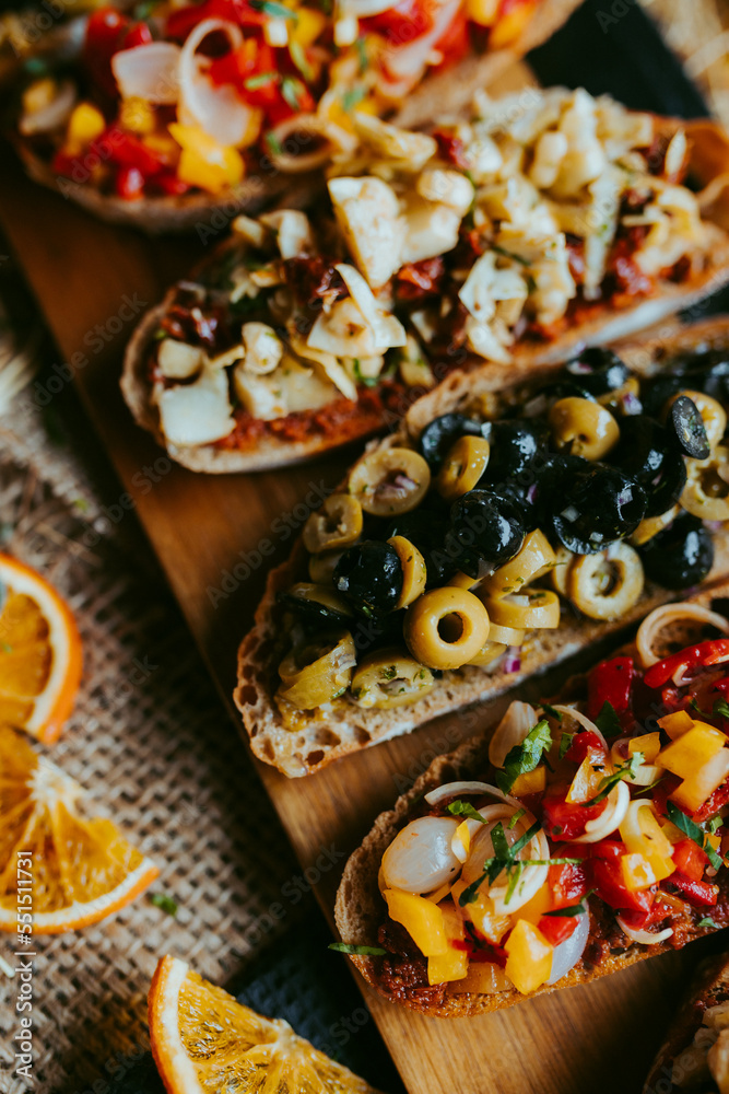 Brushetta set for party, Variety of small sandwiches with ,mushrooms, tomatoes, parmesan cheese, fresh basil and balsamic  on rustic wooden board over dark background