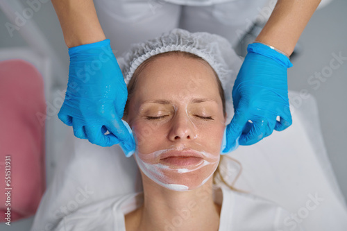 Beautician washes woman face using cotton pads to remove face mask