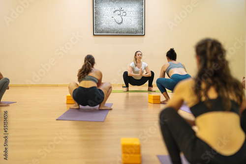 caucasian teacher teaching yoga classes in malasana pose photo