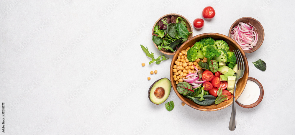 Healthy food in wooden bowl. Chickpeas, lettuce, cherry tomatoes, avocado, broccoli salad. Vegan Budha bowl on light background, top view Healthy food in wooden bowl. Chickpeas, lettuce, cherry tomatoes, avocado, broccoli salad. Vegan Budha bowl on light background, top view