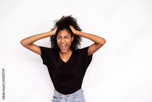 Portrait of young woman shouting in stress. African American lady wearing black T-shirt and jeans holding head in hands screaming in trouble. Problem or frustration concept photo