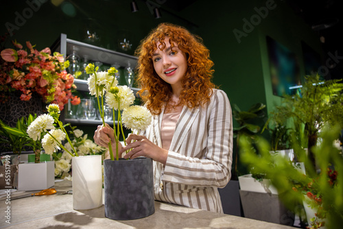 Curly-haired ginger florist holding flower pots photo