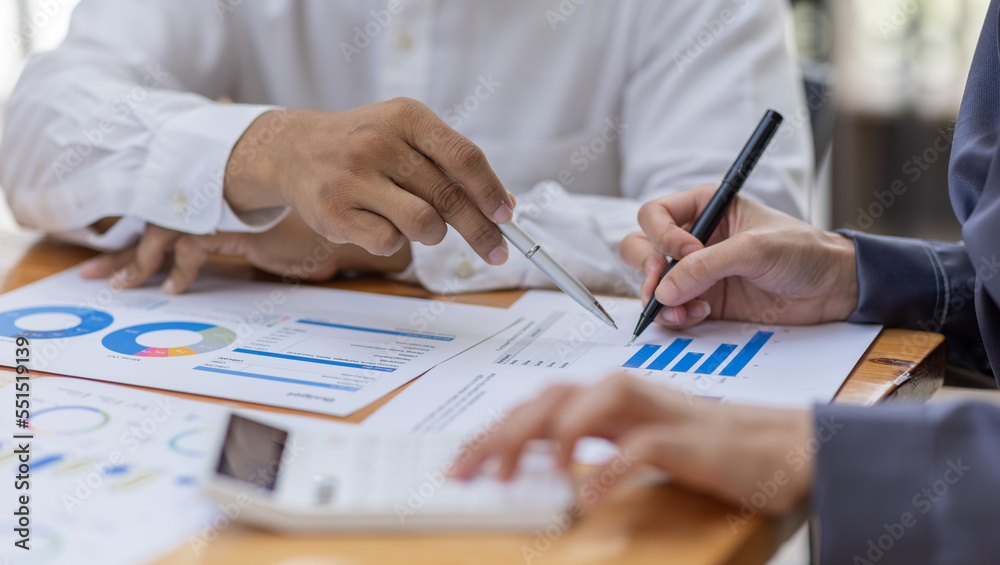 Group of confident business people point to graphs and charts to analyze market data, balance sheet, account, net profit to plan new sales strategies to increase production capacity.
