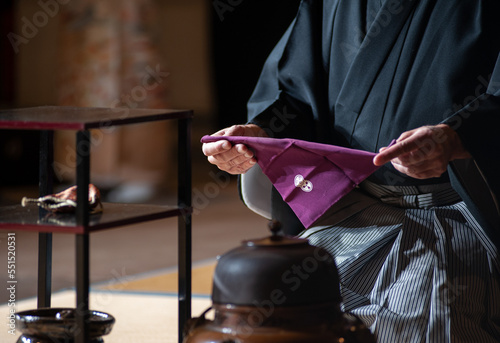 Japanese senior man in traditional kimono, during the tea ceremony. Black background..