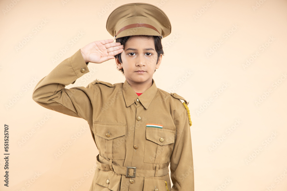 Indian boy kid wearing police custom dress salute isolated on beige studio background. Dream, Indian boy kid wearing police custom dress salute isolated on beige studio background. Dream,