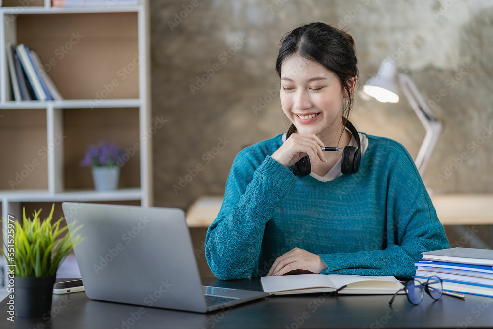 Asian businesswoman using smartphone and laptop writing on charts and graphs showing results Beautiful female accountant using calculator to calculate savings at home concept of working at home Asian businesswoman using smartphone and laptop writing on charts and graphs showing results Beautiful female accountant using calculator to calculate savings at home concept of working at home