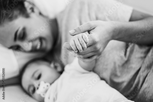 Young mother lying in bed with her son in bed at home - Focus on baby hand - Black and white editing