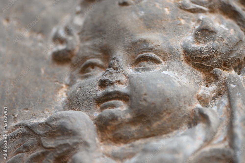 A small sandstone sculpture of an angel who has a damaged nose on the wall of a church in Murcia-Spain.