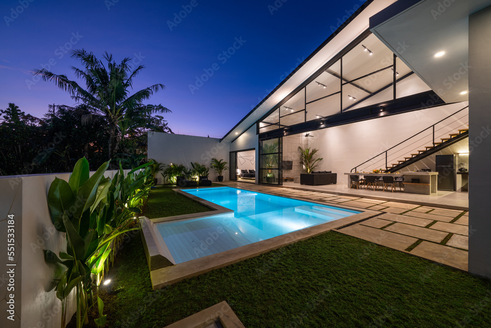 Tropical villa view with garden, swimming pool and open living room at sunset - obrazy, fototapety, plakaty 
