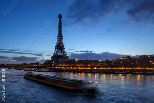 Eiffel Tower and Seine River at early morning first light with a passing barge. Port de Suffren in Paris, France
