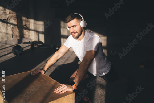 Cheerful man in headphones preparing for training in gym