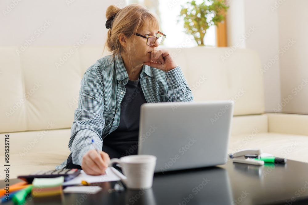 Active mature woman using a laptop for remote work from the home office. Video conference, video meeting. Senior teacher leads webinar Active mature woman using a laptop for remote work from the home office. Video conference, video meeting. Senior teacher leads webinar