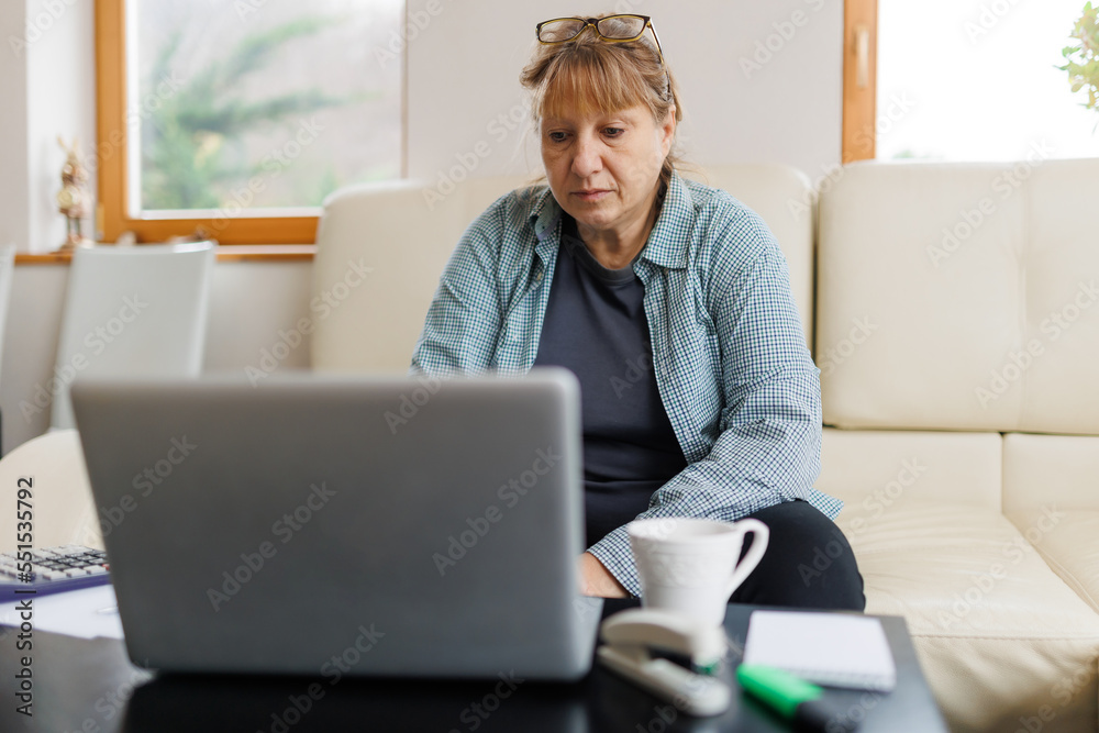 Active mature woman using a laptop for remote work from the home office. Video conference, video meeting. Senior teacher leads webinar Active mature woman using a laptop for remote work from the home office. Video conference, video meeting. Senior teacher leads webinar