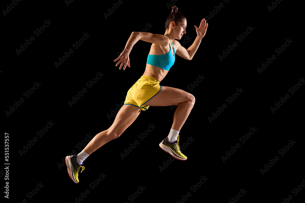 Young sportive woman, runner and jogger in motion action isolated on black background. Sport, fitness, energy, movements concept