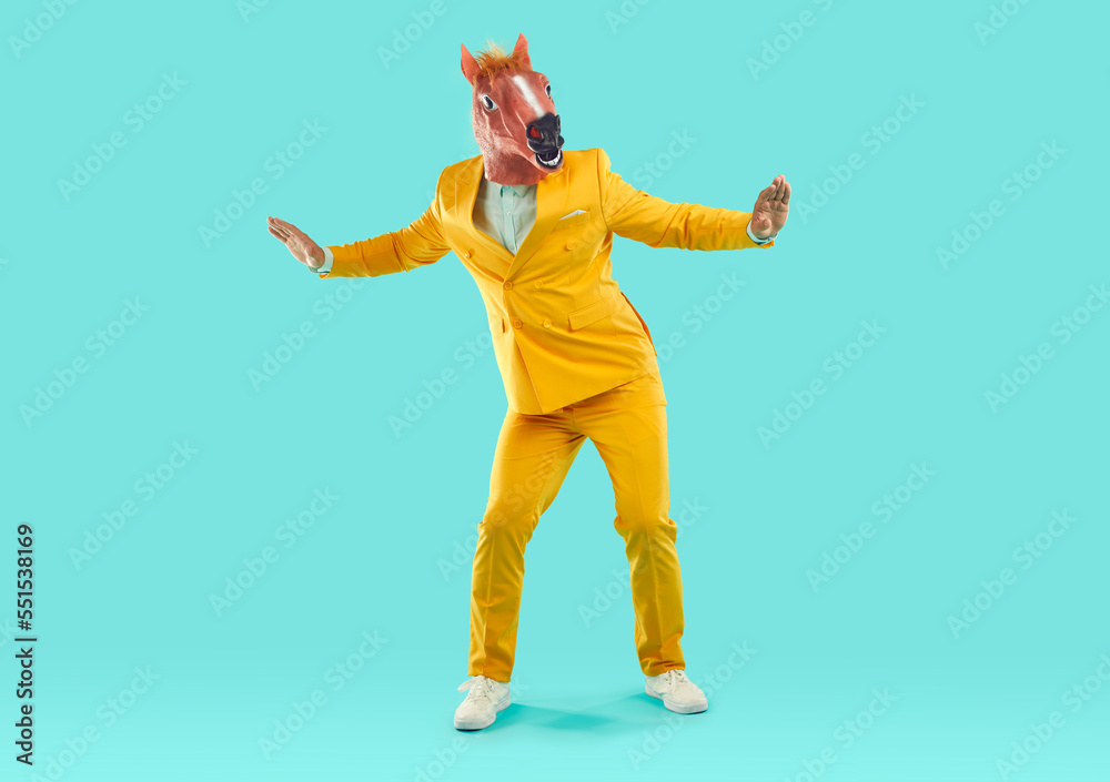 Man wearing horse head mask dancing in studio. Full length of energetic
