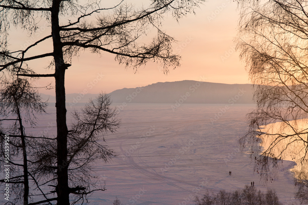 Silhouettes of Trees Against the Backdrop of a Sunset on a Frozen Winter Lake. Silhouettes of Trees Against the Backdrop of a Sunset on a Frozen Winter Lake.