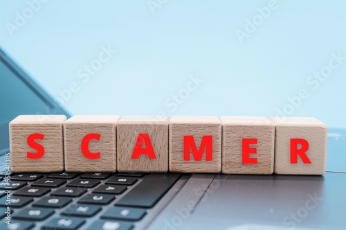 the word scamer or scam on wooden cube blocks on a keyboard with copy space. scaming, phishing, vishing concept
 photo