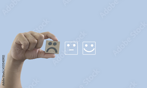 Man hand holding emotion face block, customer satisfaction concept. sad face, Service rating, ranking, customer review, copy space, satisfaction, evaluation and feedback concept
