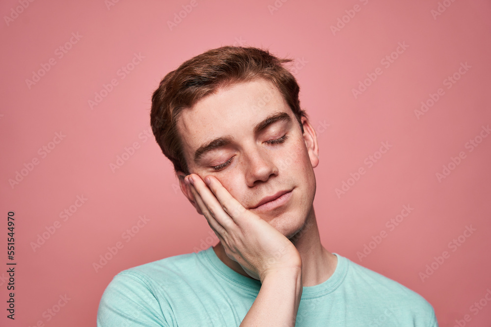 Young man touching cheek and sleeping Young man touching cheek and sleeping
