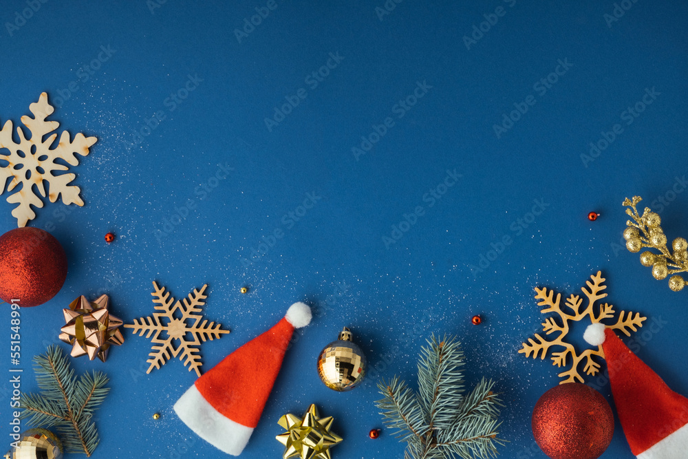 Foto de Christmas toys on the blue background. Festive Christmas background  with wooden snowflakes, tree branches and Santa hats. Flat lay. Copy space.  Merry Christmas and Happy New Year do Stock |