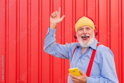 a modern retiree listening to music with headphones and dancing photo