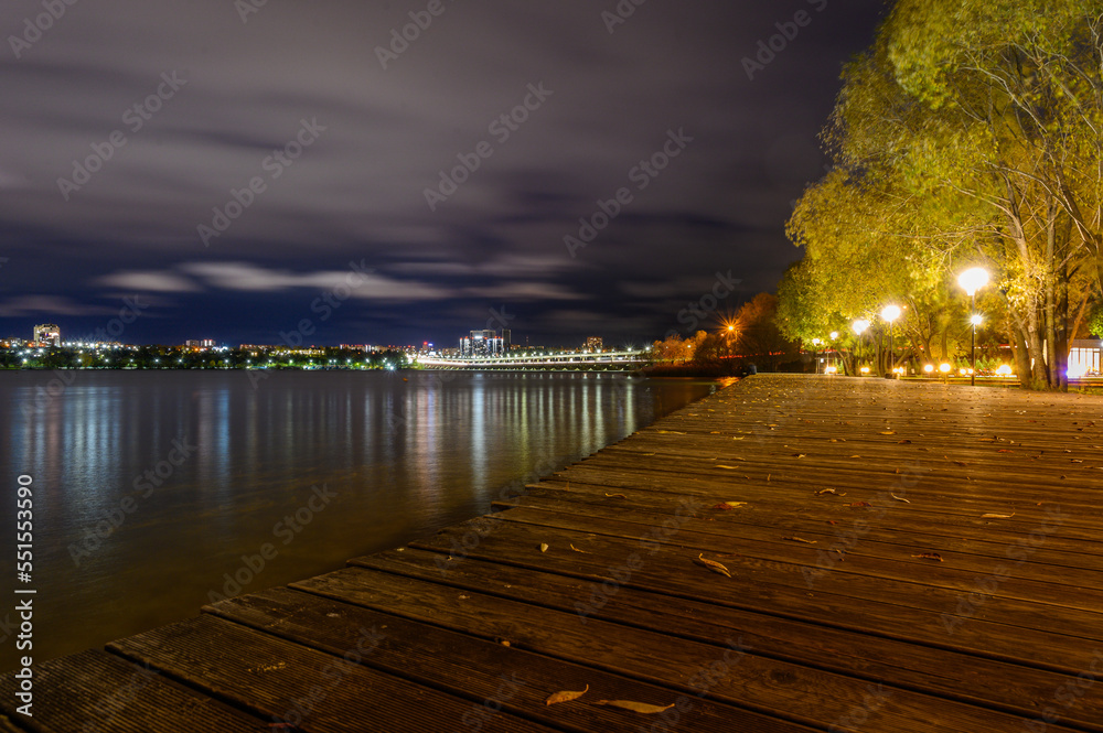Autumn embankment with leaves near the river in the evening
