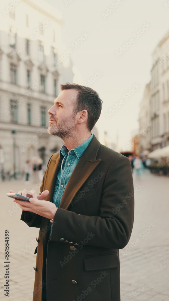 Middle aged man using map app on mobile phone on the old town background Middle aged man using map app on mobile phone on the old town background