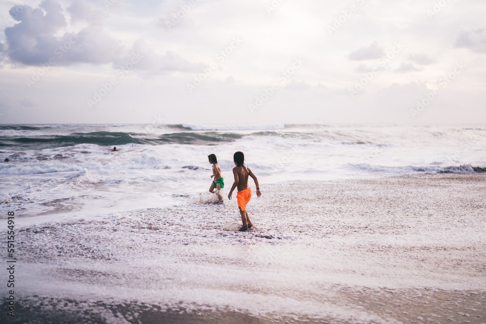 Unrecognizable children playing with waves Unrecognizable children playing with waves