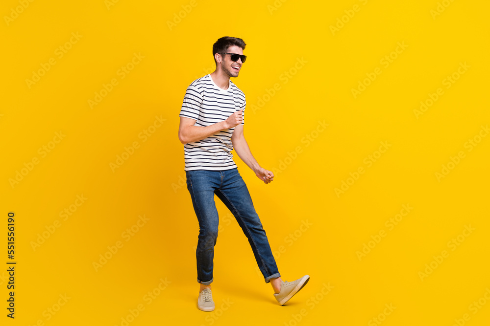 Fototapeta premium Full length photo of funky adorable man wear white t-shirt dark glasses having fun dancing isolated yellow color background