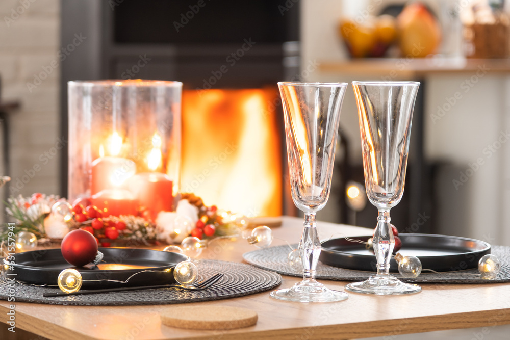 Festive interior of house is decorated for Christmas and New Year in loft style with black stove, fireplace, Christmas tree. Warm studio room with set table, burning wood, cozy and heating of home Festive interior of house is decorated for Christmas and New Year in loft style with black stove, fireplace, Christmas tree. Warm studio room with set table, burning wood, cozy and heating of home