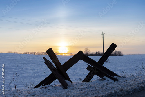 Iron anti-tank barrier made to block Russian offensive in Ukraine. military industry. War on territory of Ukraine. metal construction. defensive structure in winter on border of a snow-covered field