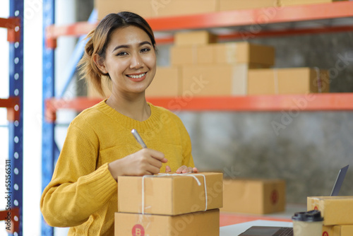 Woman startup small business entrepreneur works with cardboard boxes in a warehouse. Ecommerce business idea.