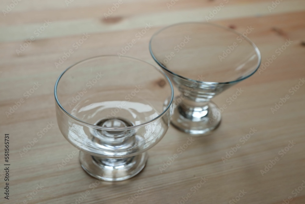 Empty ice cream glassware stands on the wooden surface of the table. Empty ice cream glassware stands on the wooden surface of the table.