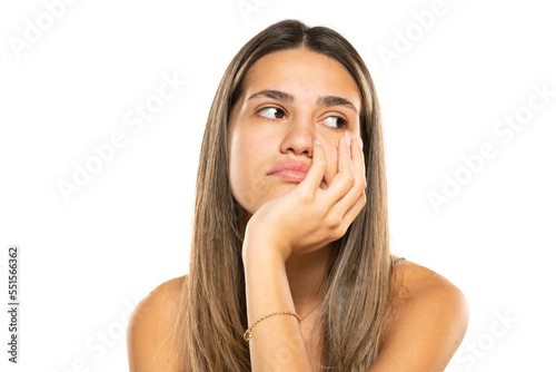 Boring young woman with long hair looking to side and thinking on a white background